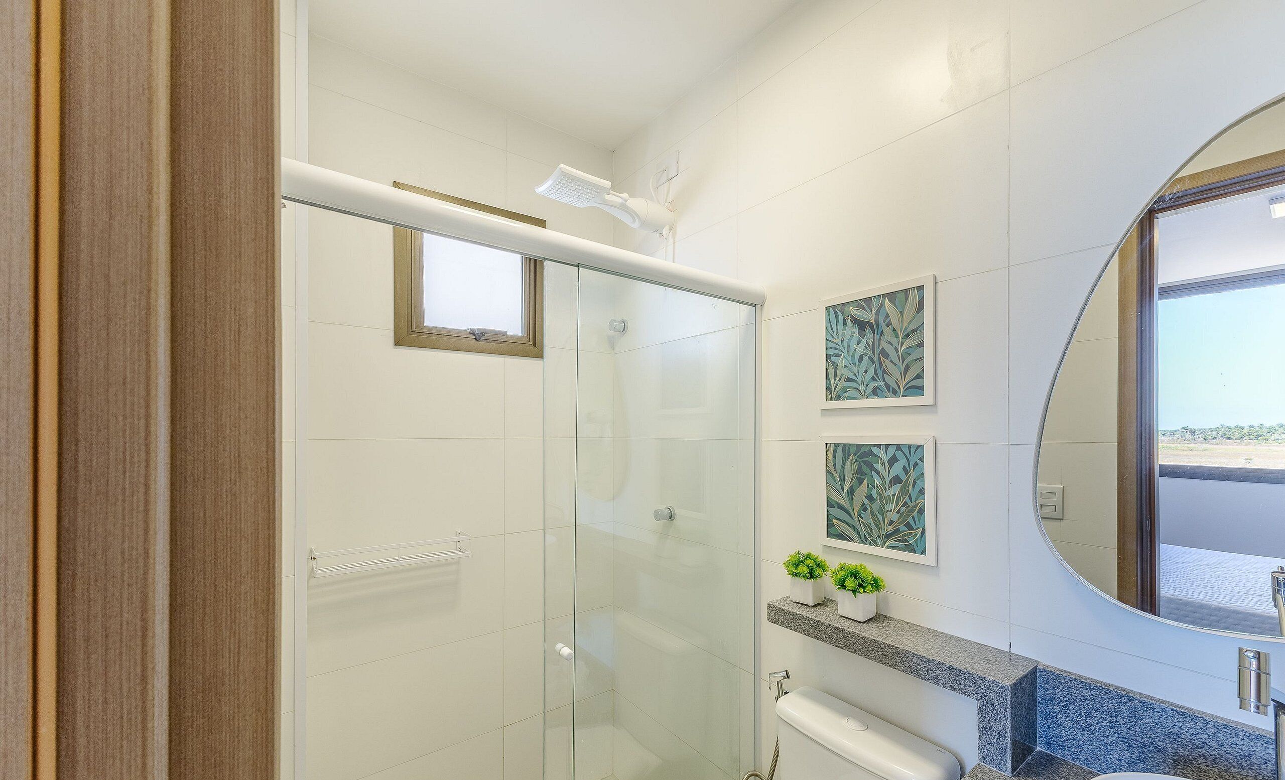 Un baño moderno con cabina de ducha de vidrio, encimera de mármol y un espejo grande.