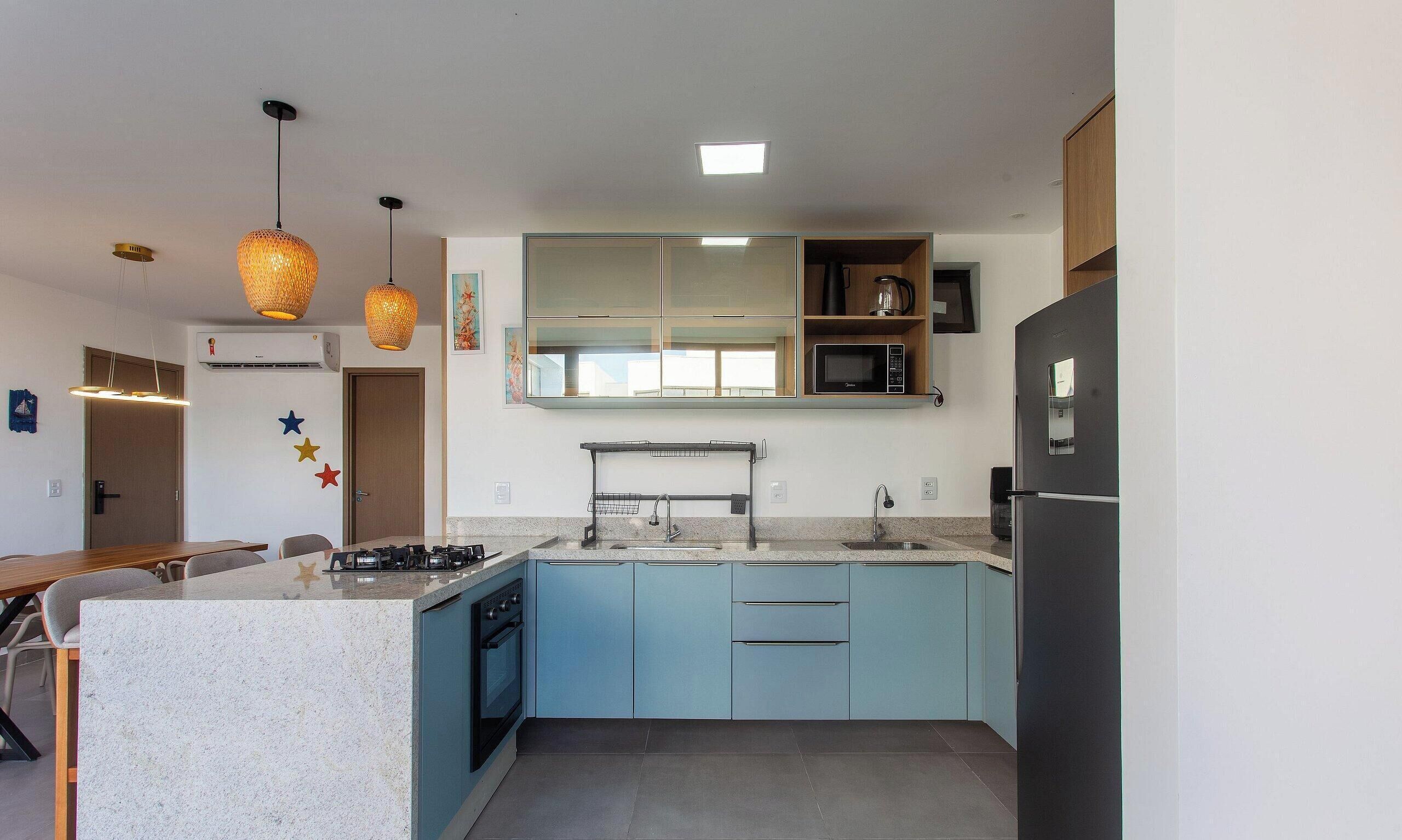 Una cucina moderna con isola centrale, elettrodomestici integrati e illuminazione a sospensione.