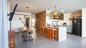 A modern kitchen with a central island, bar stools, a dining table with chairs, and a refrigerator. - Apartment in Condominium With Pool Vll0002 (Maraú)