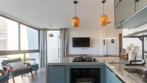 A modern kitchen with a built-in oven, a dining area with a table and chairs, and a large window. - Apartment in Condominium With Pool Vll0002 (Maraú)