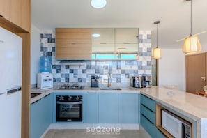 A modern kitchen with a built-in oven, a coffee maker, and a water dispenser. - Apt With Lagoon and Pool View Vll0101 (Maraú)