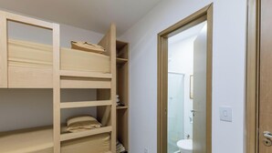 A room with a bunk bed, a bathroom with a toilet and a sink, and a door leading to another room. - Apt With Lagoon and Pool View Vll0101 (Maraú)