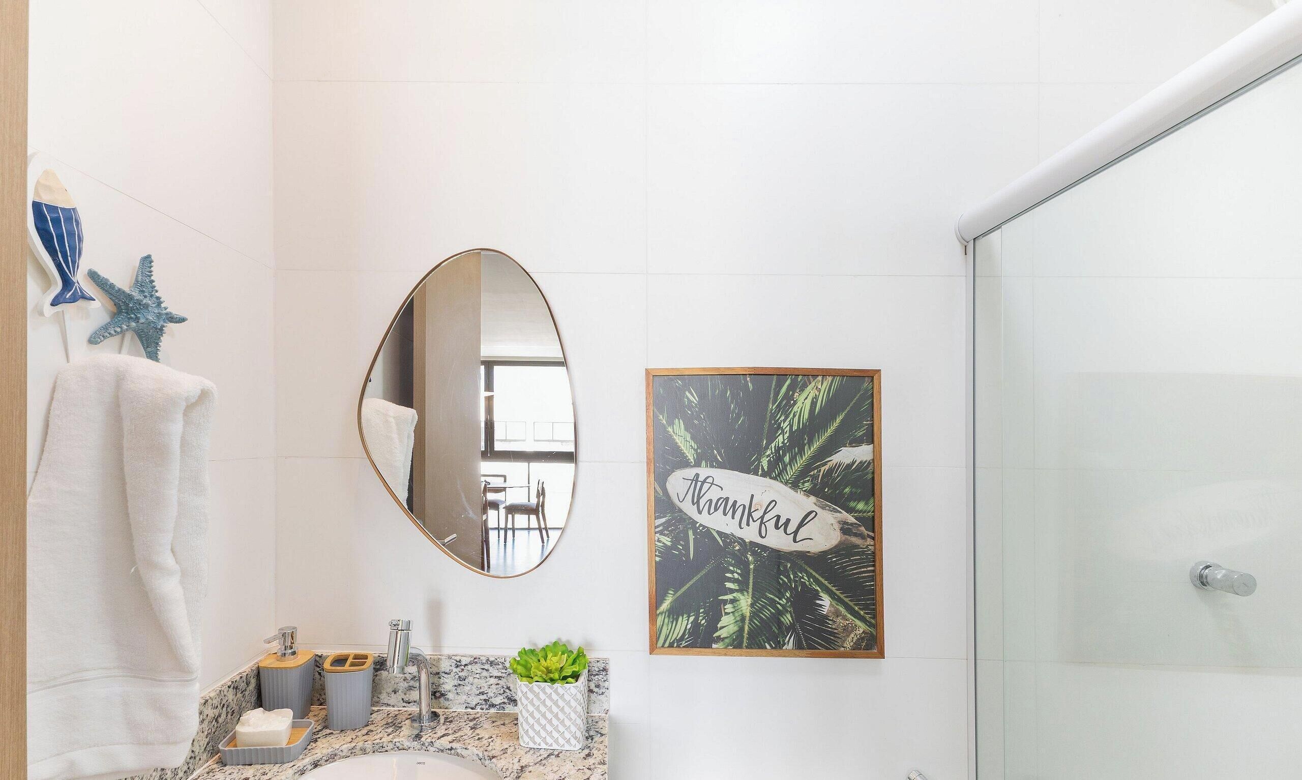 A bathroom with a marble countertop, a sink, a mirror, a towel rack, a framed thankfulness sign, and a shower area.