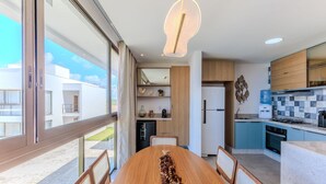 A modern kitchen with a dining area, large windows, and a view of the outside. - Apt With Lagoon and Pool View Vll0101 (Maraú)
