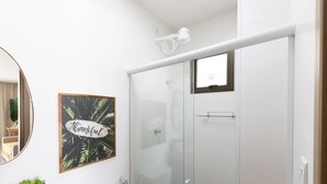 A bathroom with a glass shower enclosure, a framed thank you sign, a mirror, and a marble sink. - Apt With Lagoon and Pool View Vll0101 (Maraú)