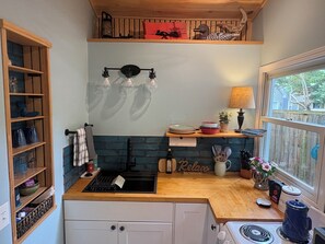 A kitchen with a wooden countertop, a sink, a stove, and a window with a view.