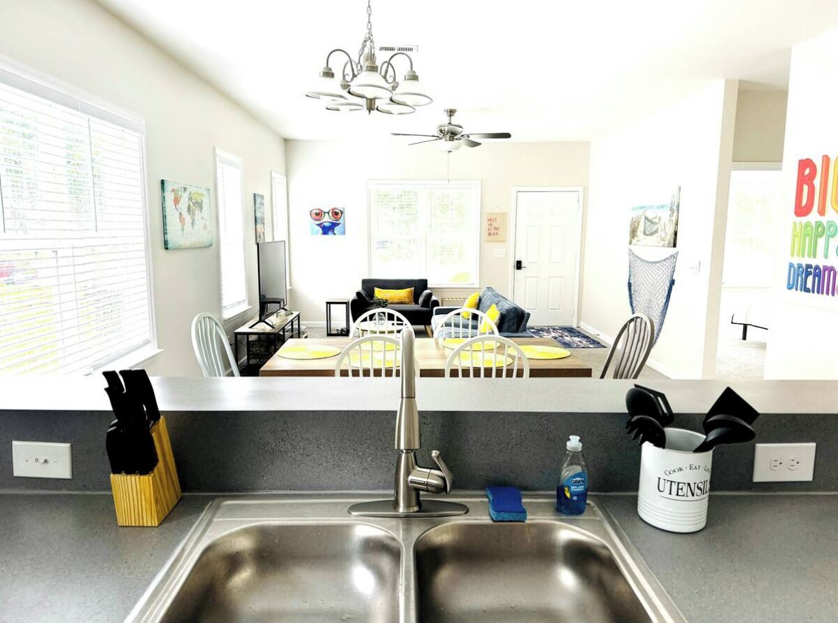 Uma cozinha moderna com pia dupla, área de refeições com mesa e cadeiras, e ventilador de teto.