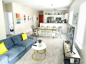 A modern living room with a sofa, coffee table, and a dining area with chairs. - 3BR/2BA Charleston Home – Minutes to Downtown & Folly Beach! (Charleston)