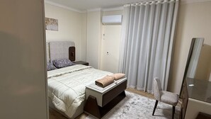 Een slaapkamer met een bed, nachtkastje, stoel en een spiegel.