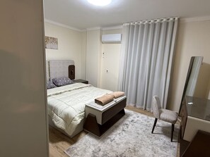 Une chambre à coucher comprenant un lit, une table de chevet, une chaise et un miroir.