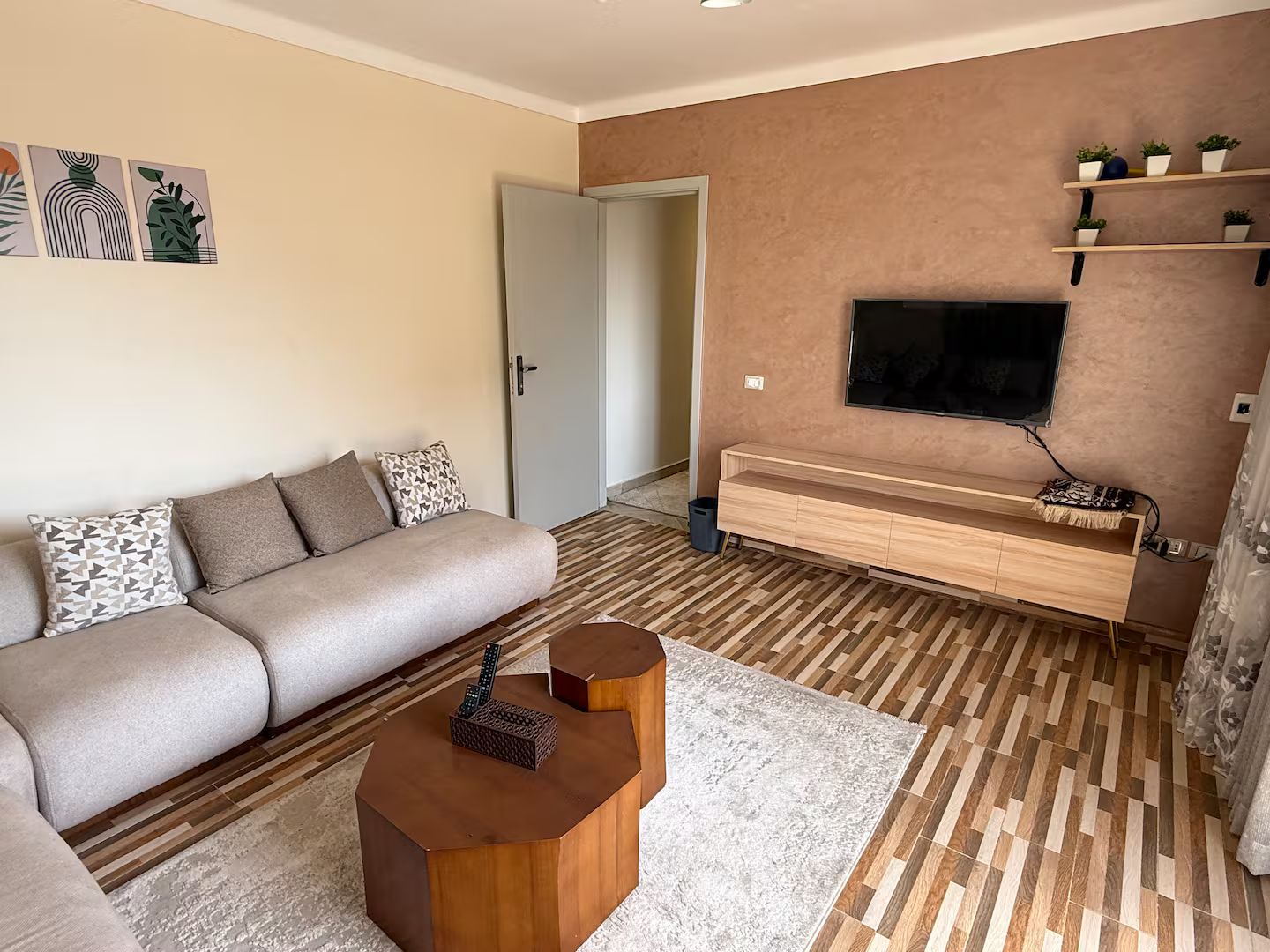 Ein modernes Wohnzimmer mit einer Couch, einem Couchtisch, einem Fernseher und einem Holz-TV-Möbel.