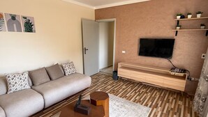 Een moderne woonkamer met een bank, salontafel, televisie en een houten tv-meubel.
