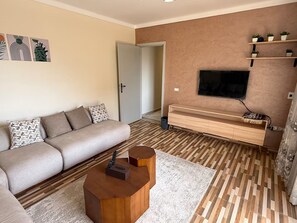 Un salon moderne comprenant un canapé, une table basse, un téléviseur et un meuble TV en bois.