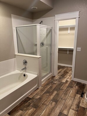 A bathroom with a bathtub, a glass-enclosed shower, and a wooden floor. - Wonderful Unfurnished 3-bedroom townhome with AC in friendly Broomfield (Broomfield)