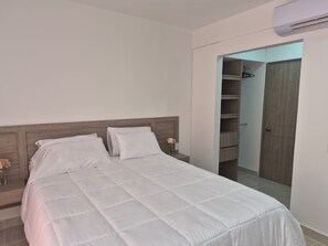 Ein Schlafzimmer mit einem Bett, Nachttischen, einem Kleiderschrank und einer Klimaanlage.