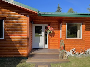 A log cabin with a wooden exterior, a front door, a window, and a small porch area. - Sterling Riverfront Retreat - Private Kenai River Access (Sterling)
