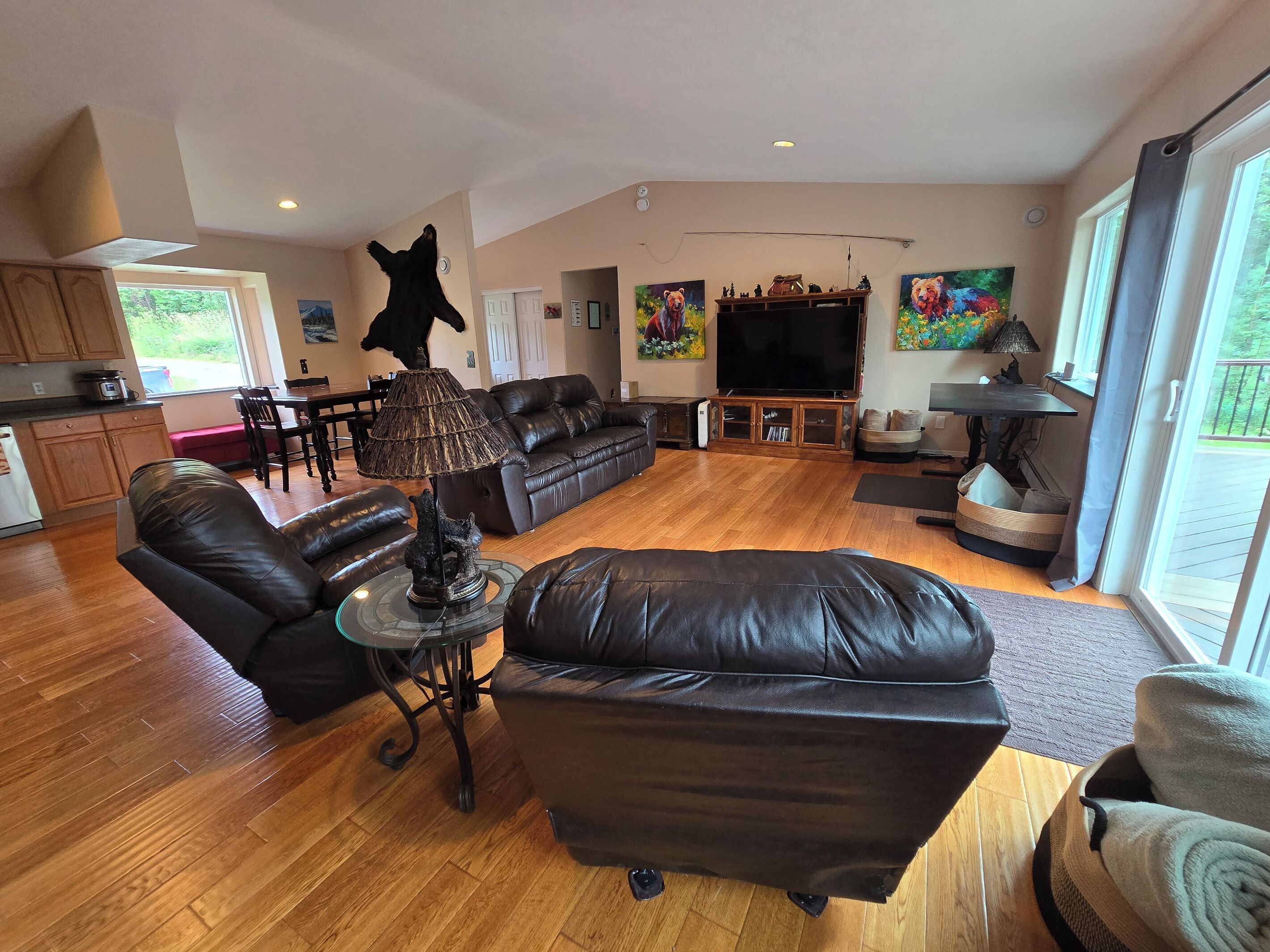 A spacious living room with a leather sofa, a dining area, and a kitchen in the background.
