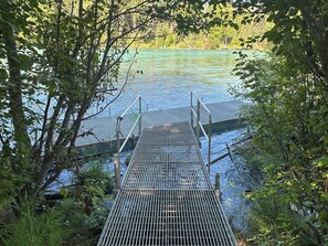 A metal dock leading into a body of water surrounded by dense foliage.