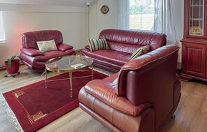 Ein Wohnzimmer mit einem roten Ledersofa, einem Glastisch und einem roten Teppich.
