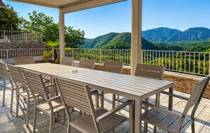 Un patio al aire libre con mesa y sillas, con vistas a un paisaje montañoso.