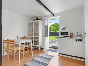 Une cuisine compacte avec un coin repas, des meubles blancs et une vue sur le jardin.