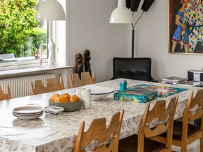 Ein Essbereich mit einem Marmortisch, Holzsesseln, einem Gesellschaftsspiel und einem Bild an der Wand.