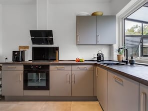 Eine moderne Küche mit eingebautem Backofen, einer Mikrowelle und einer Kaffeemaschine.