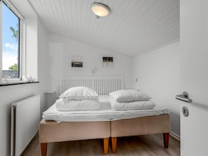 Ein Schlafzimmer mit einem Bett, einem Fenster, einer Heizung und einer Tür.