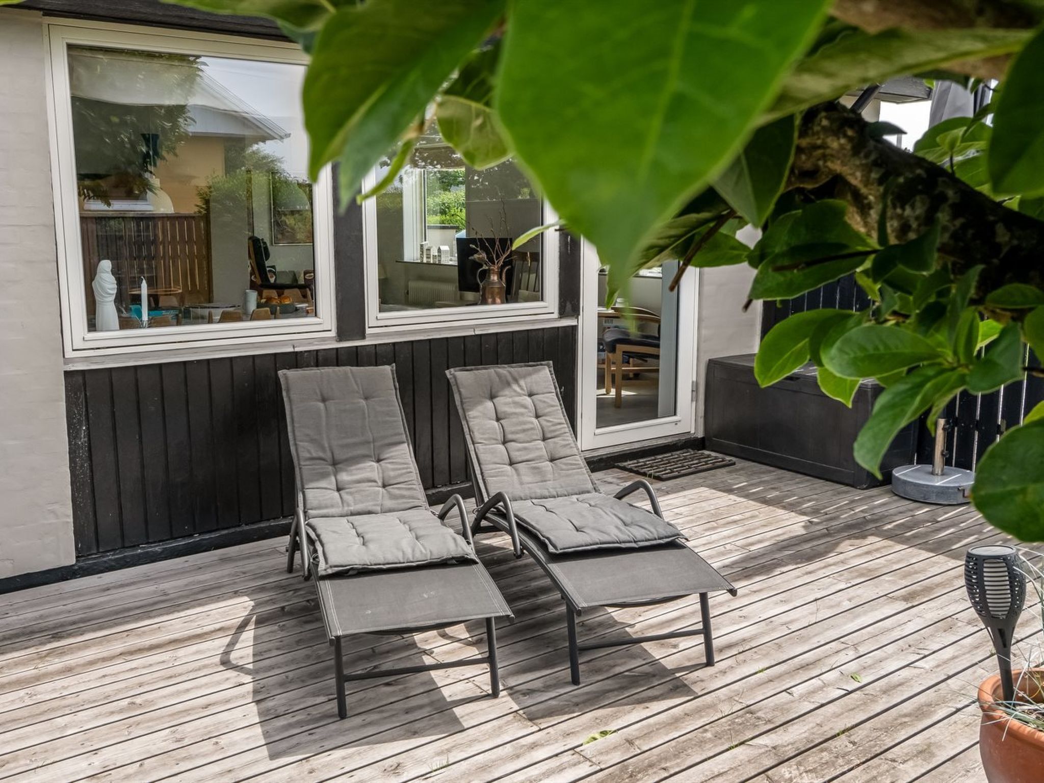A deck with two lounge chairs and a potted plant.