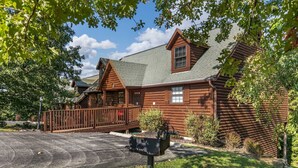 A log cabin with a porch, a mailbox, and a well-maintained lawn.