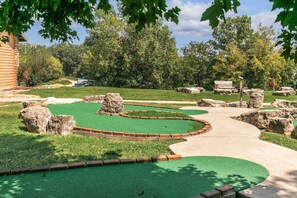 A miniature golf course with a winding path, green artificial turf, and scattered rocks. - Spacious Cabin Sleeps 14 - Two Living Areas - Indoor Pool, Pet Friendly, Branson Woods Resort - 17 (Branson)