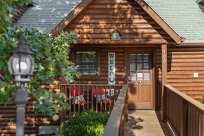 A wooden cabin with a 'WELCOME' sign, a porch with seating, and a number '17' on the door. - Spacious Cabin Sleeps 14 - Two Living Areas - Indoor Pool, Pet Friendly, Branson Woods Resort - 17 (Branson)