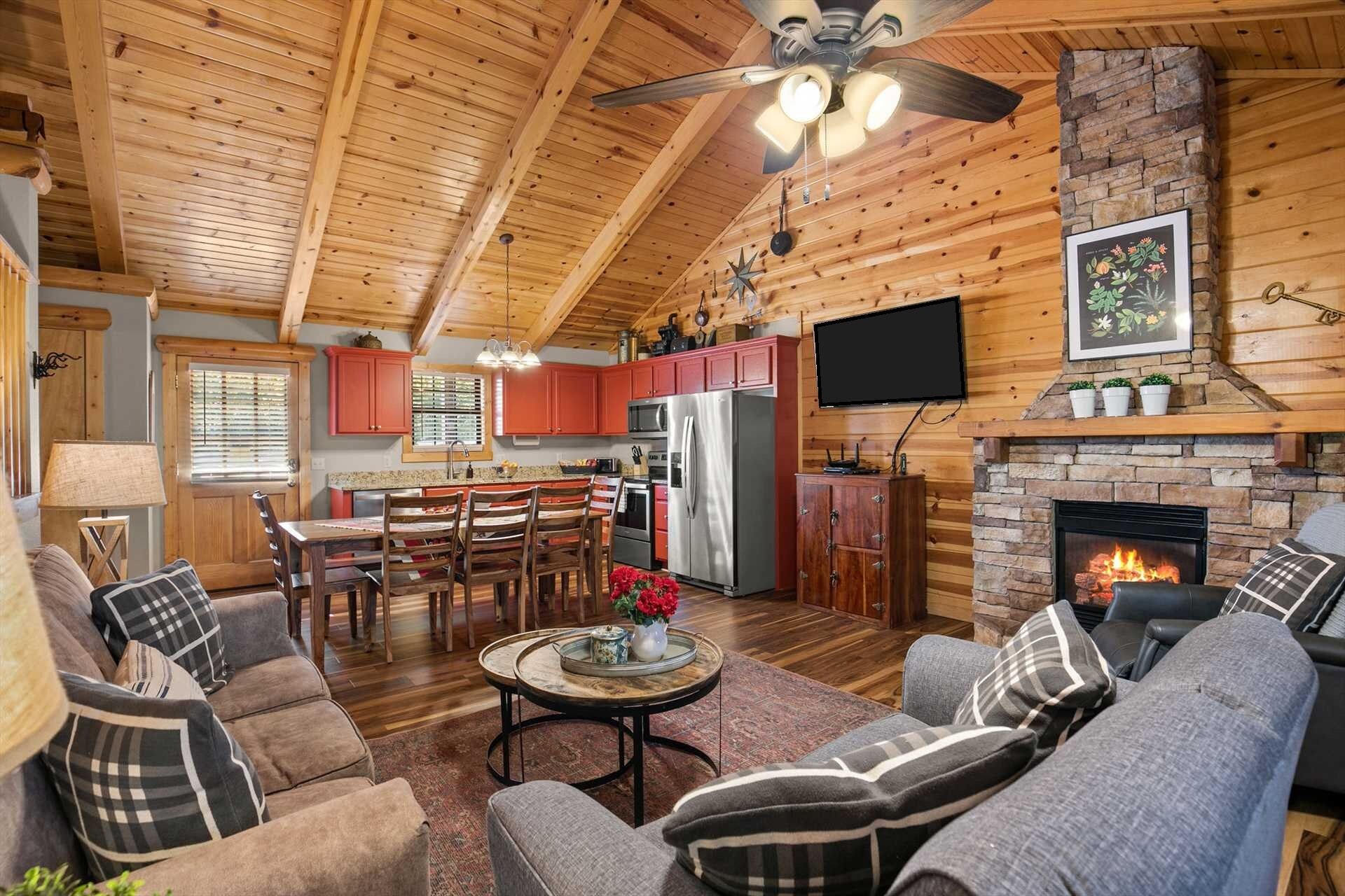A cozy cabin interior with a dining area, kitchen, fireplace, and seating.