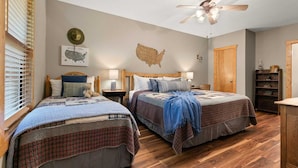 A bedroom with two beds, a ceiling fan, a map of the USA on the wall, and a wooden floor.