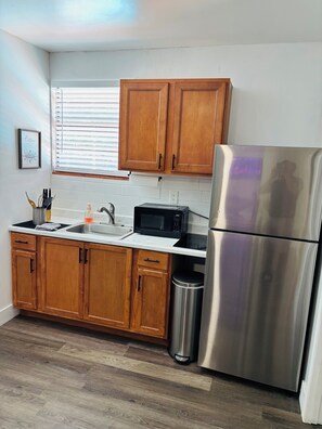 A kitchen with wooden cabinets, a stainless steel refrigerator, a microwave, and a sink. - Charming 2-bedroom guest house with Pool in Port St. Lucie (Port St. Lucie)