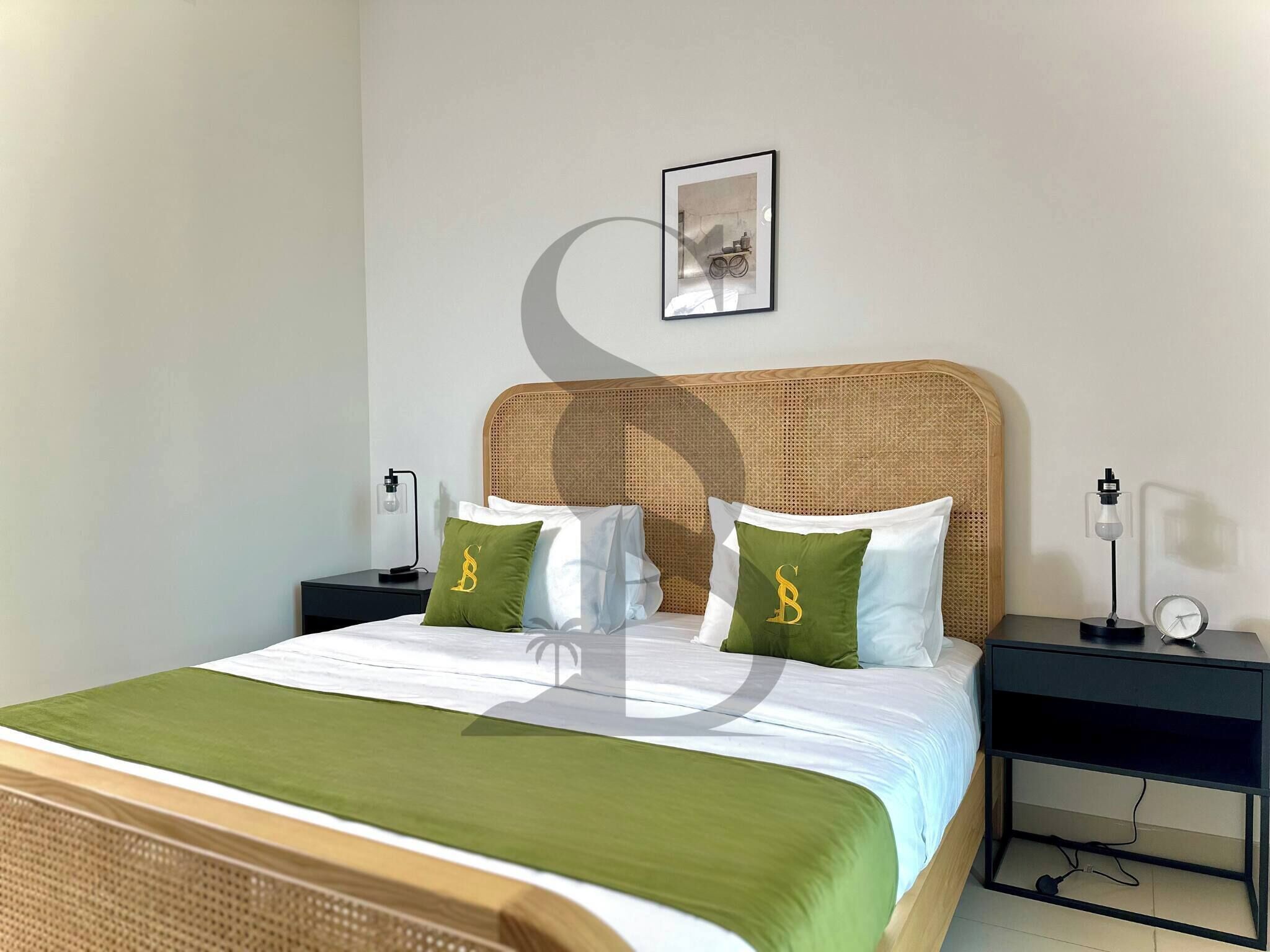 Et pænt opredt hotelværelse med en seng, to sengeborde, et billede på væggen og en sengetøjslampe.