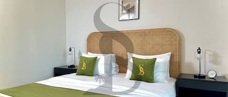 Quarto de hotel bem arrumado com uma cama, duas mesas de cabeceira, um quadro na parede e um abajur.
