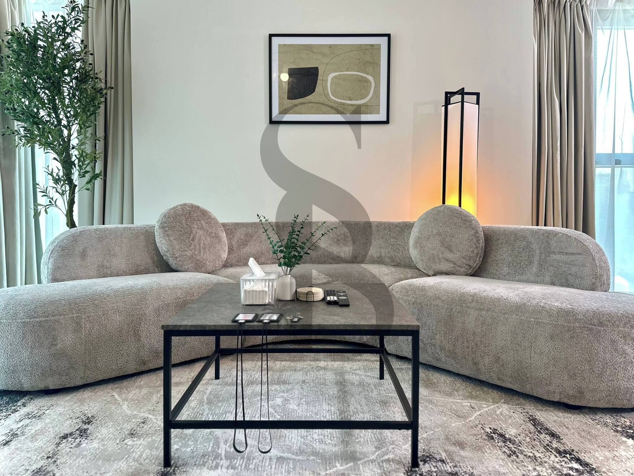 Ein modernes Wohnzimmer mit grauem Sofa, Couchtisch und Stehlampe.