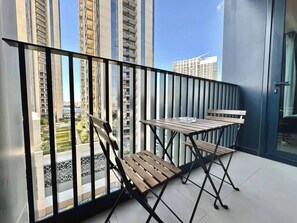 A balcony with a table and chairs, a view of high-rise buildings, and a clear sky. - Discounted Luxury 1Br 4 sleeps Dubai Creek Harbour (Dubai)