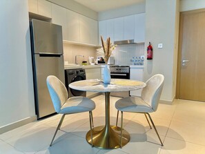 A modern kitchen with a central island, two chairs, a refrigerator, and a fire extinguisher. - Discounted Luxury 1Br 4 sleeps Dubai Creek Harbour (Dubai)