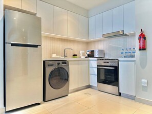A modern kitchen with stainless steel appliances, including a refrigerator, washing machine, microwave, and oven. - Discounted Luxury 1Br 4 sleeps Dubai Creek Harbour (Dubai)