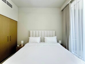 A hotel room with a large bed, a wooden wardrobe, and a window with curtains. - Discounted Luxury 1Br 4 sleeps Dubai Creek Harbour (Dubai)