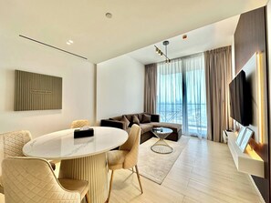 A modern living room with a round table, two sofas, and a television mounted on the wall. - Lowest Price  Amazing City  View Luxury 1 Br (Dubai)