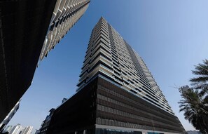 A high-rise building with a modern architectural design, featuring a prominent corner and multiple balconies. - Lowest Price  Amazing City  View Luxury 1 Br (Dubai)