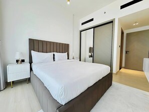 A modern hotel room with a large bed, a bedside table with a lamp, and a wardrobe. - Lowest Price  Amazing City  View Luxury 1 Br (Dubai)