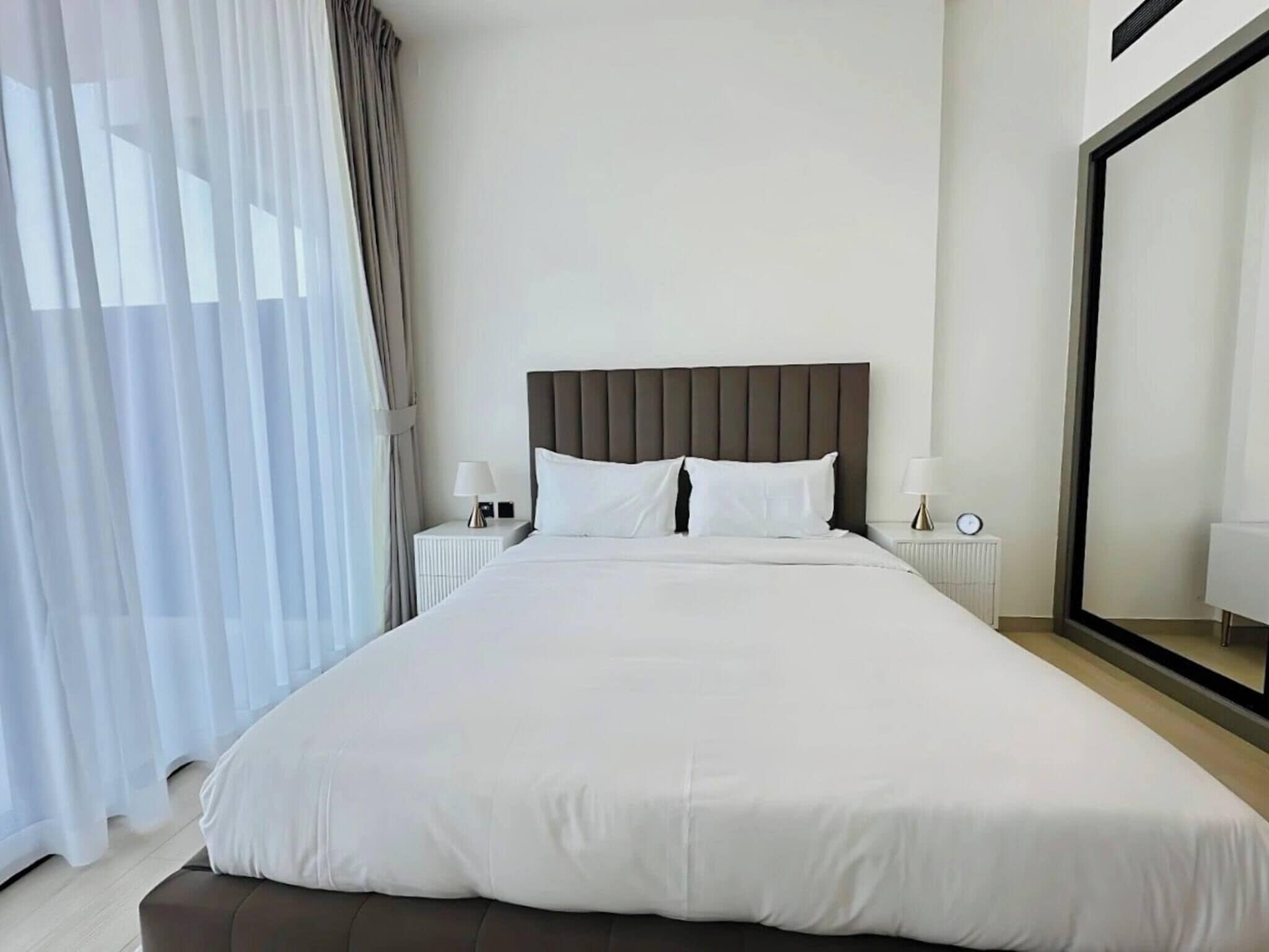 A hotel room with a large bed, two bedside tables, and a large mirror.