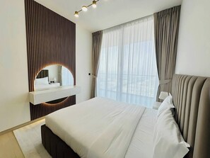 A modern hotel room with a large bed, a bedside table, a mirror, and a window with curtains. - Lowest Price  Amazing City  View Luxury 1 Br (Dubai)