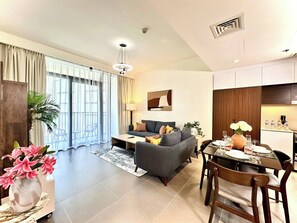 A modern living room with a sofa, dining table, and a balcony with curtains. - Amazing View Special Discount Luxury 1 Br Apt (Dubai)