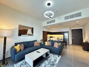 A modern living room with a sectional sofa, a coffee table, and a floor lamp. - Amazing View Special Discount Luxury 1 Br Apt (Dubai)