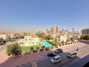 Zona residencial amb piscina, cotxes aparcats i edificis alts al fons.